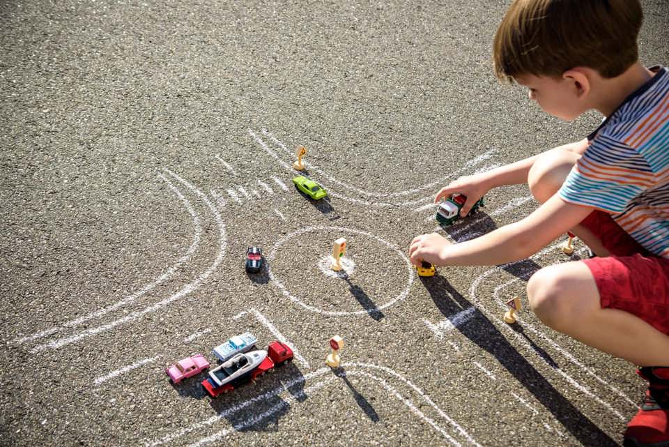 Jongen speelt op straat met auto's: Verkeer op kindermaat