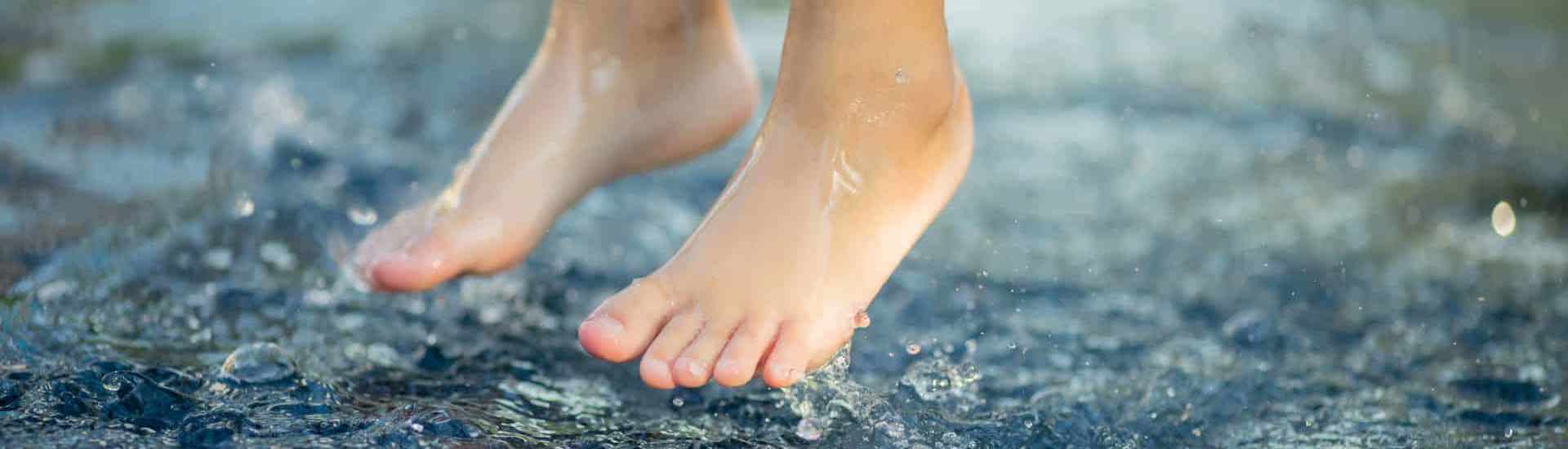 Kind springt blootvoets in de plassen