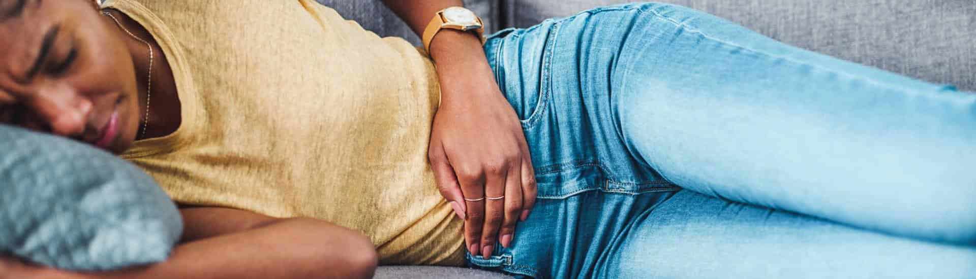 Vrouw met menstruatiepijn ligt in zetel