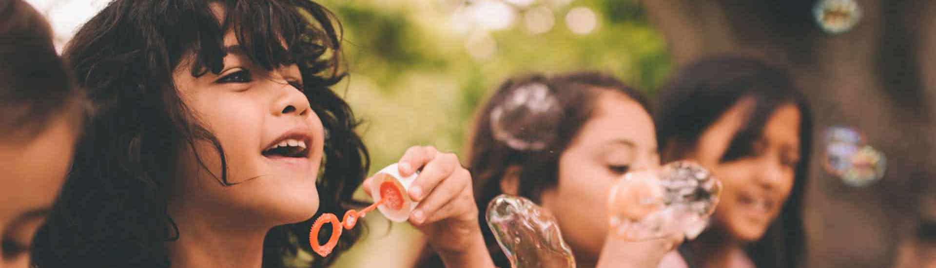 Kinderen spelen buiten en blazen zeepbellen