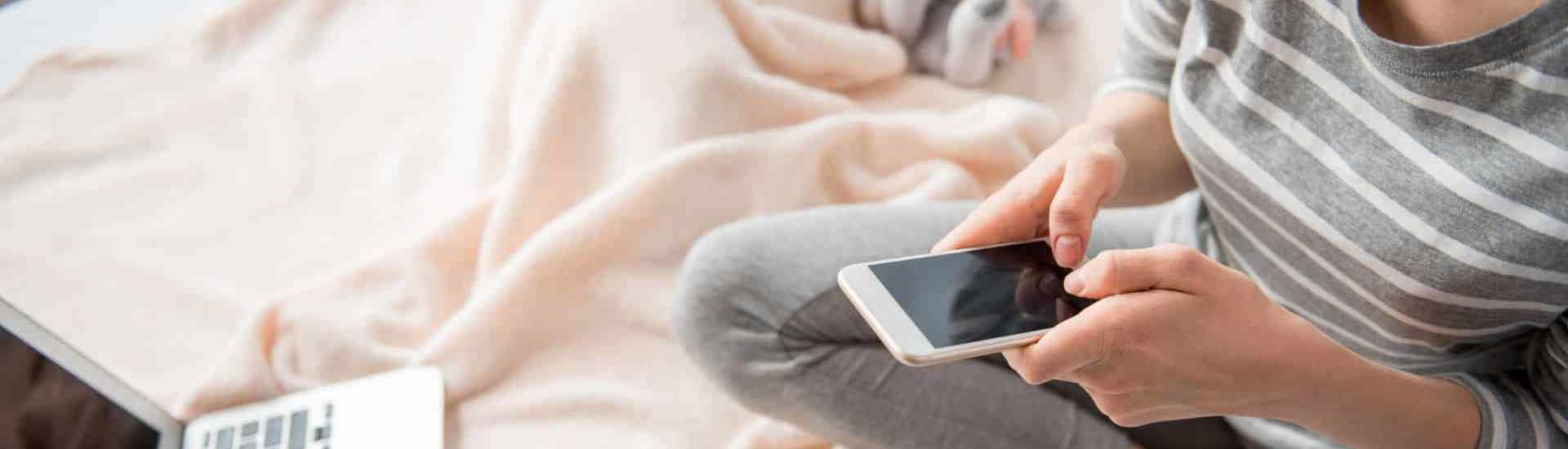 Mama met slapende baby en smartphone: smartphoneverslaving