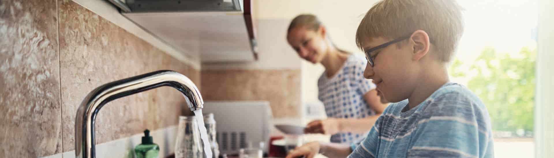Kind helpt met huishoudelijke klusjes in de keuken