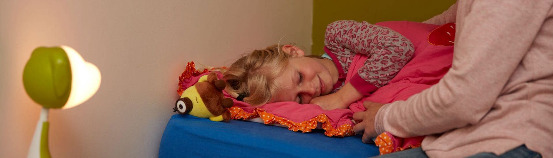 Ouder probeert te praten met kind dat in bed ligt