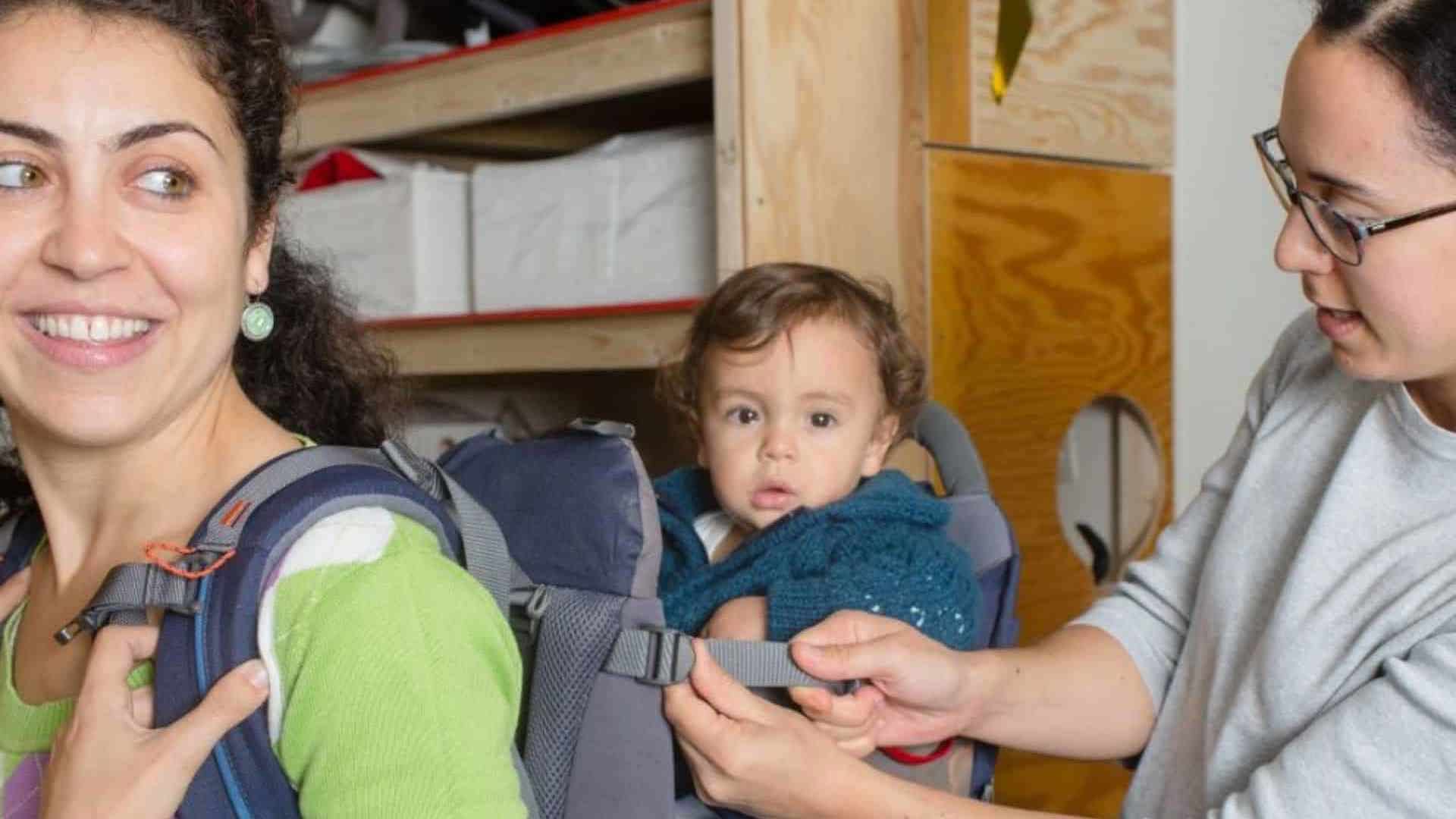 Vrouw met baby koopt draagzak in babytheek