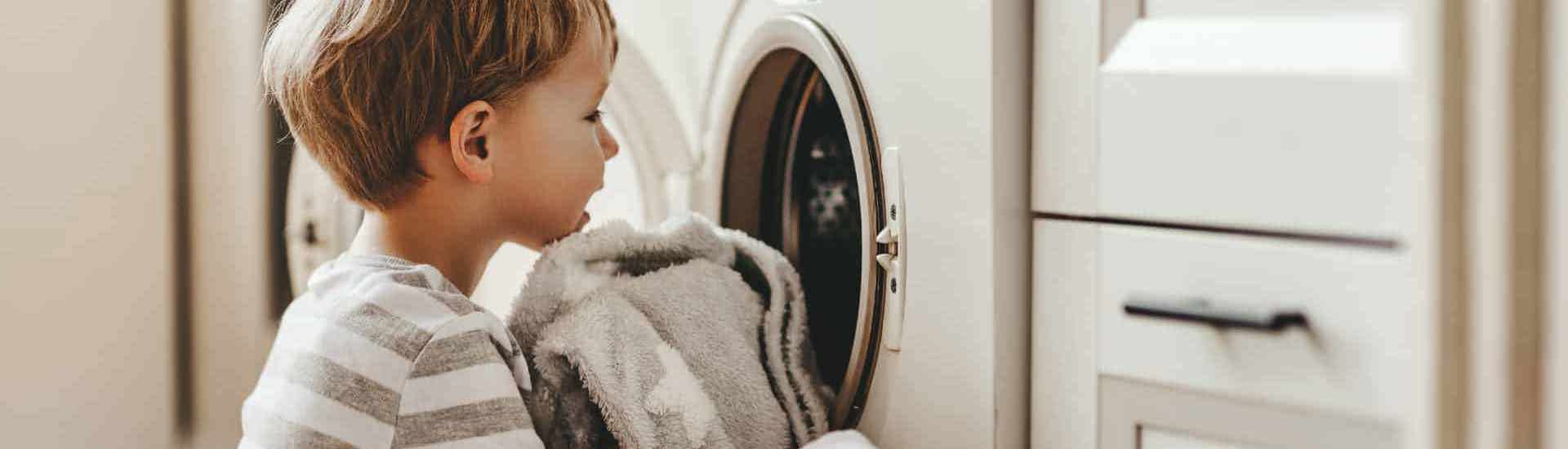 Kind vult de wasmachine en helpt bij het huishouden