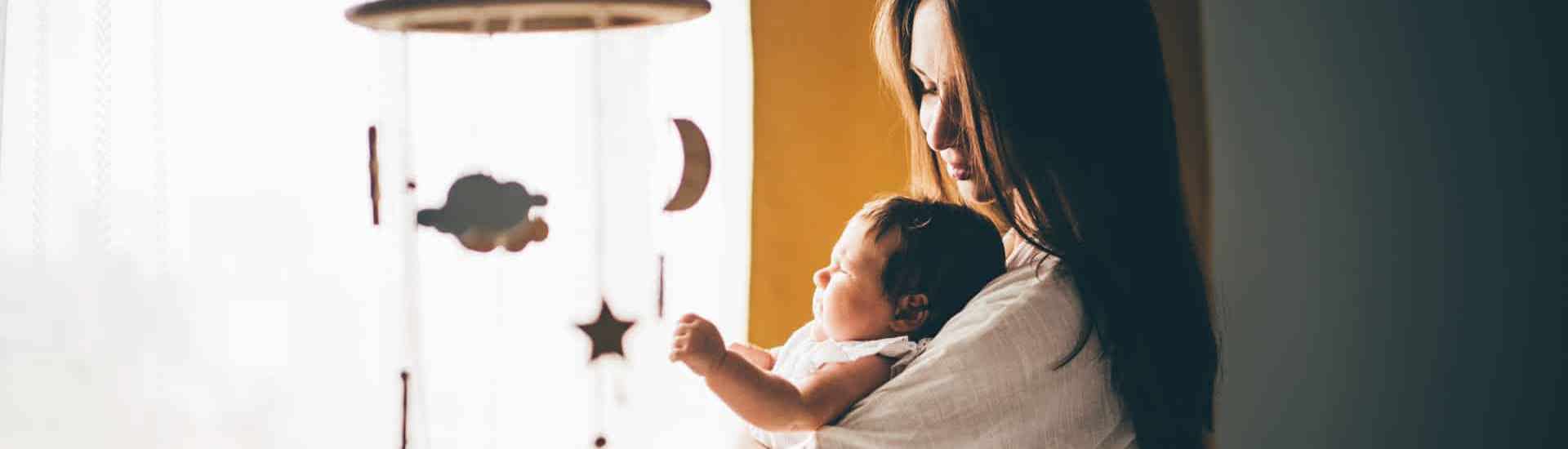 Mama geeft baby bij babybedje: een slaapritueel geven