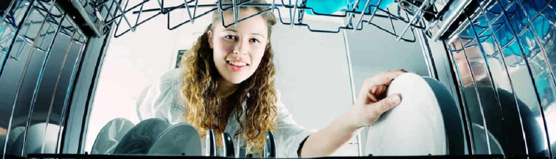 Tiener helpt in het huishouden en laadt de afwasmachine in