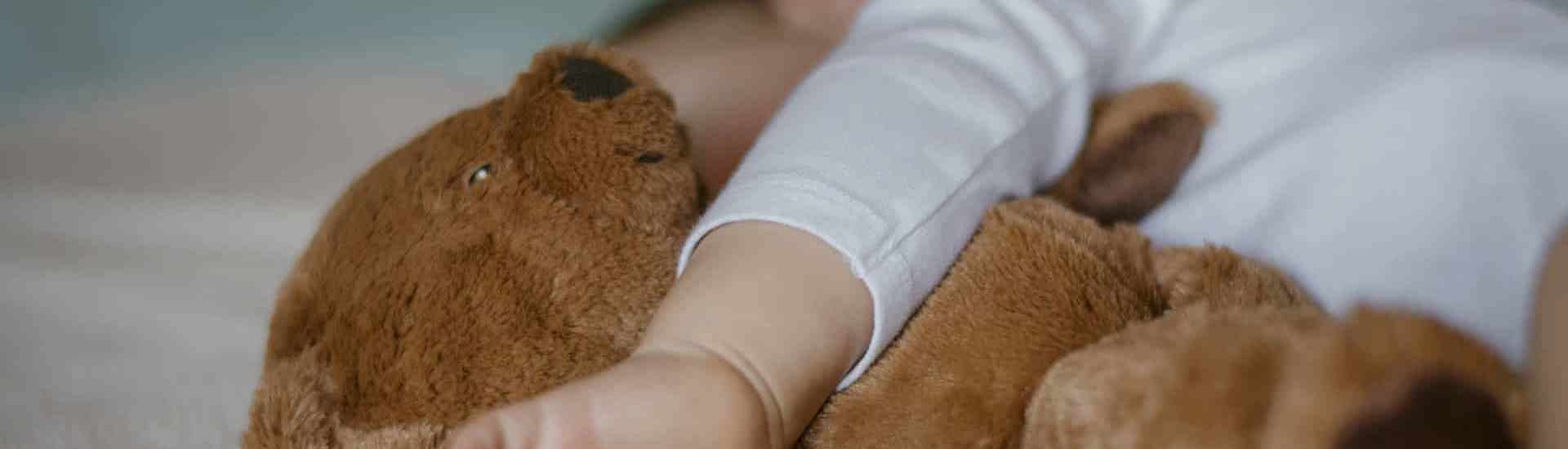 Baby met knuffel slapend in bed
