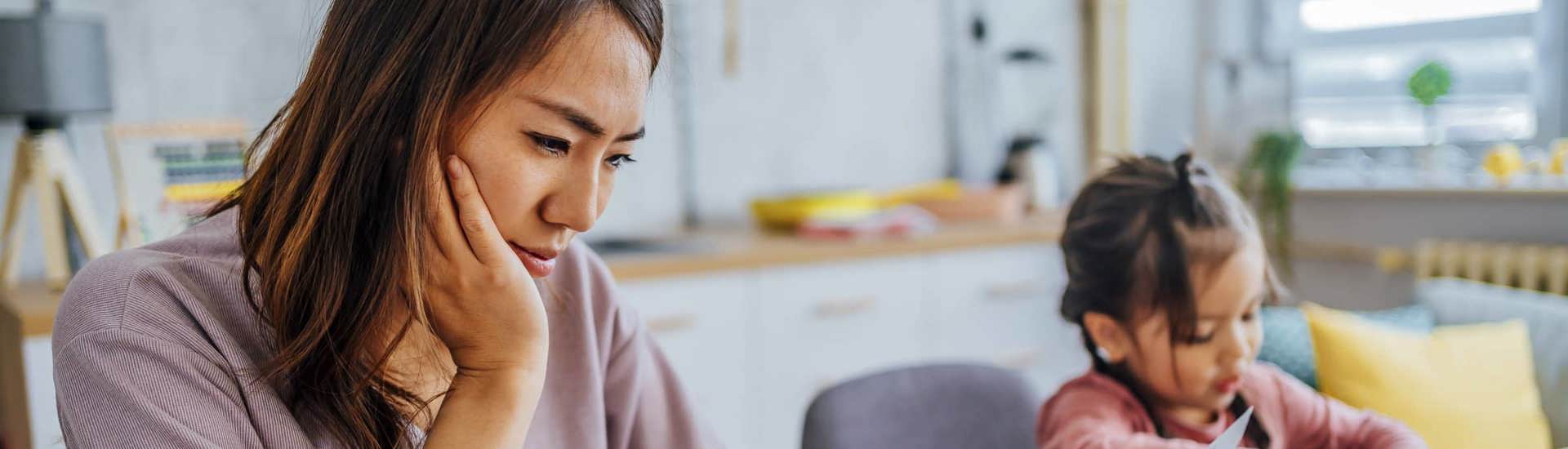 Mama bekijkt het gezinsbudget met dochter op de achtergrond: tips van  Djennah Van Nieuwenhove