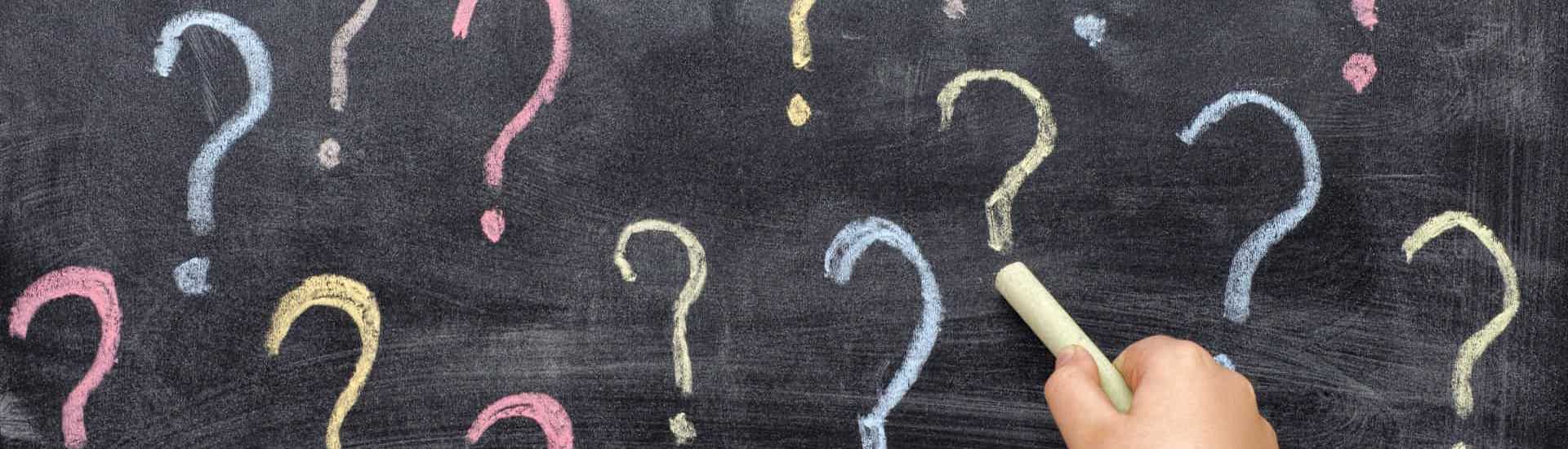 Kinderhand tekent vraagteken op bord: waarom vragen kleuter