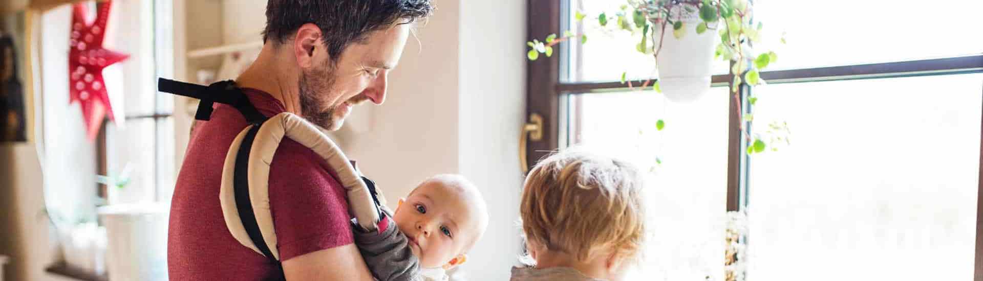 Papa draagt baby in een draagzak
