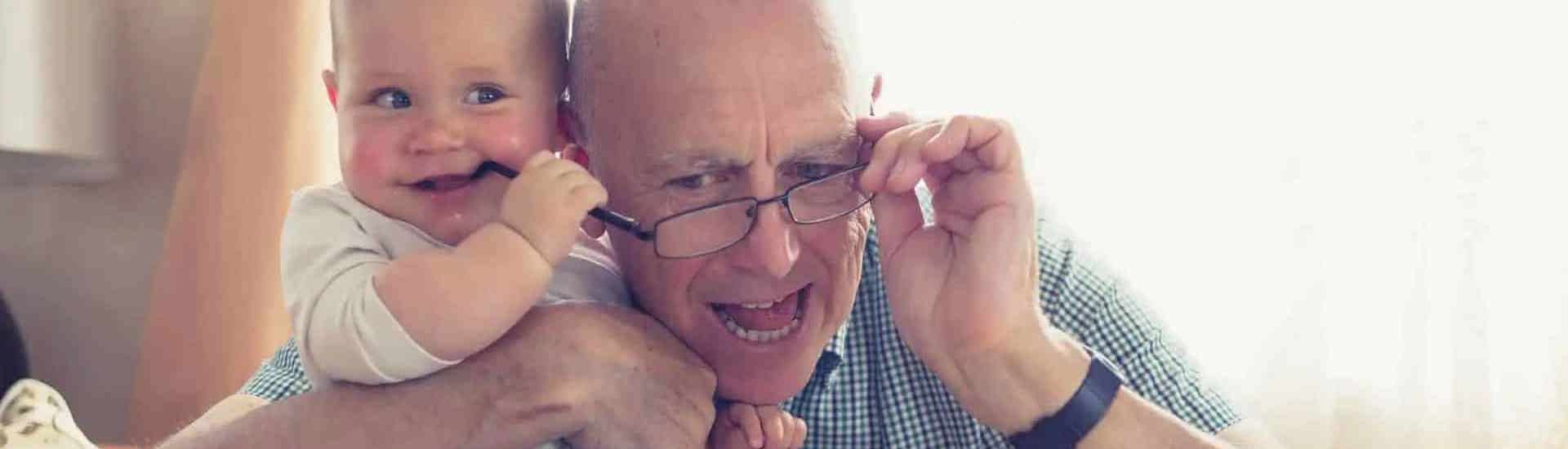 Grootvader met kleindkind dat sabbelt op de bril van opa