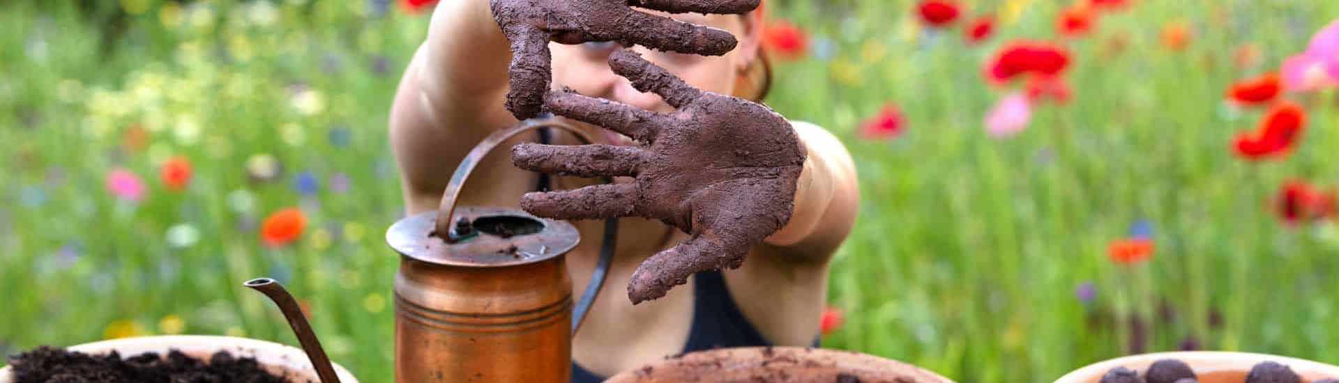 Kind speelt met aarde in de tuin: Vakantietip voor de zomer: maak bloemzaadbommetjes