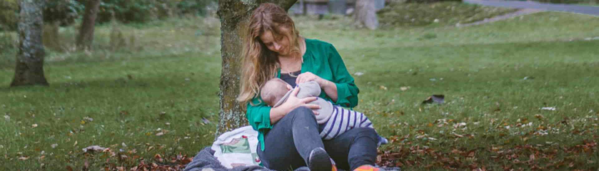 Mama geeft borstvoeding in park: recht op borstvoedingsverlof
