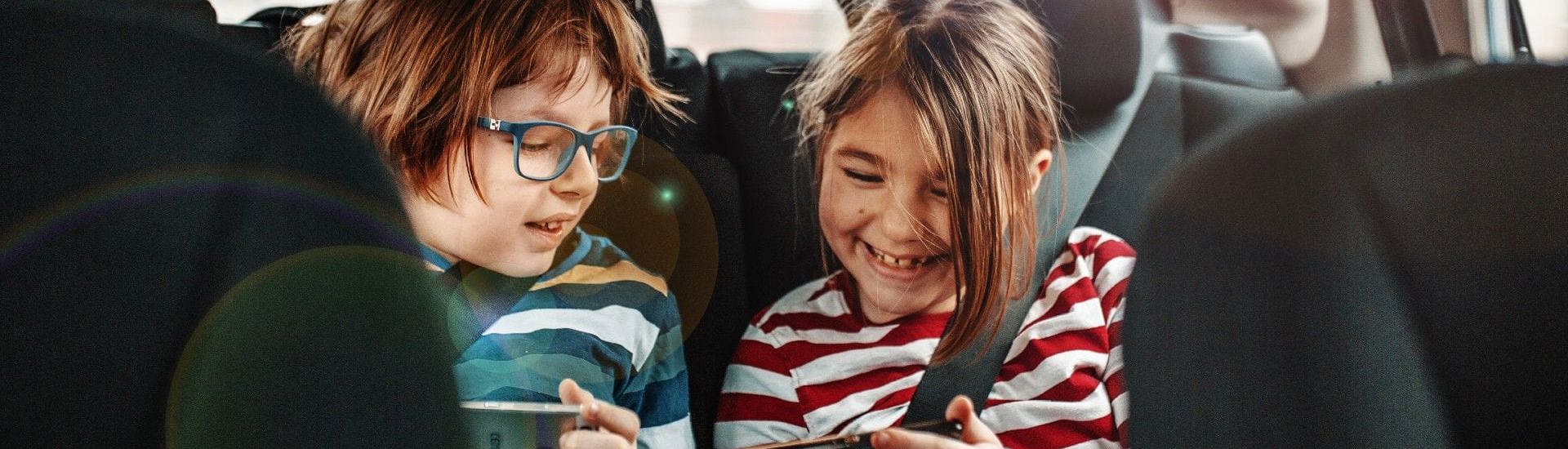 Kinderen zitten met smartphones in de auto