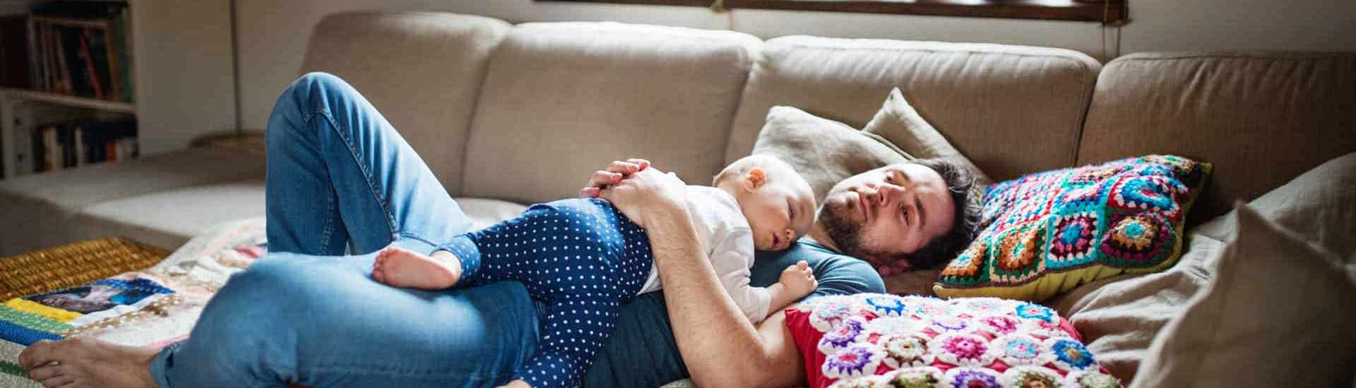 Vermoeide papa slaapt met baby in zetel
